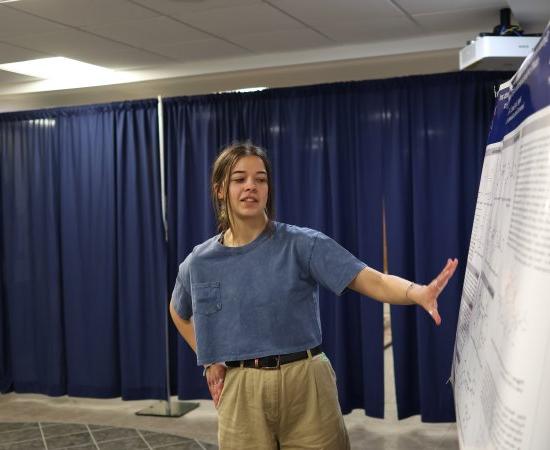 A student makes a presentation beside a poster at the 2024 Student Conference for Research, 专业活动, 及创意艺术